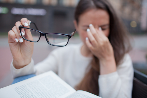 Girl itching eyes with glasses off