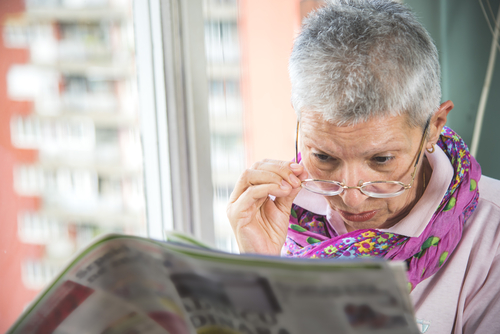 Older woman with cataracts struggling to read over glasses