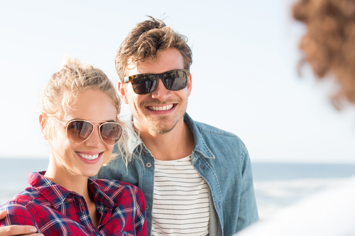 Smiling young couple wearing sunglasses on the beach
