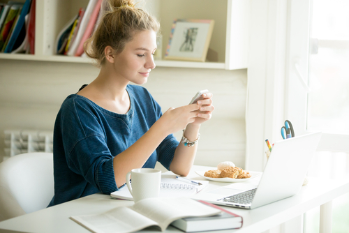 girl sitting at desk looking on phone 