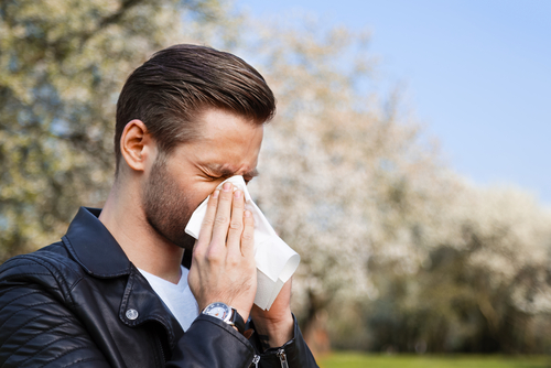 man sneezing into tissue 