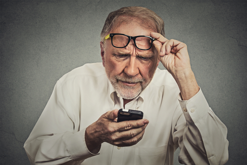 Man with glasses on his forehead squinting at his phone